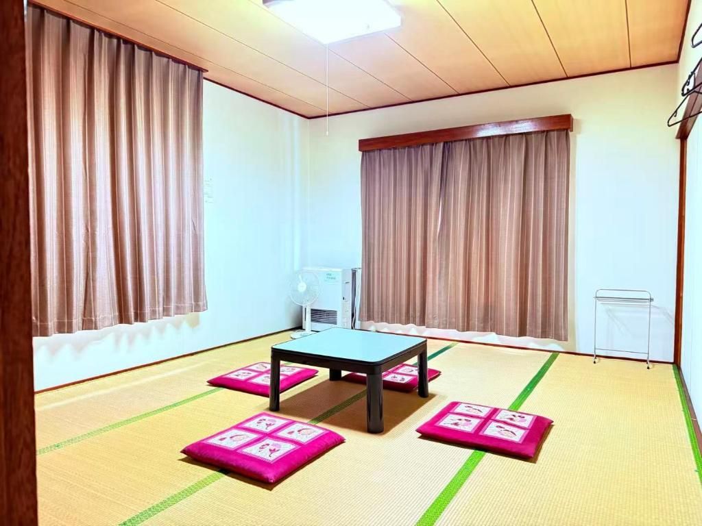 A room with tatami mats, a table, and two windows with curtains.