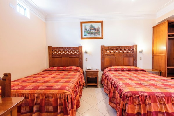 Una habitación de hotel con dos camas de madera, una mesita de noche, un cuadro enmarcado en la pared y un armario.