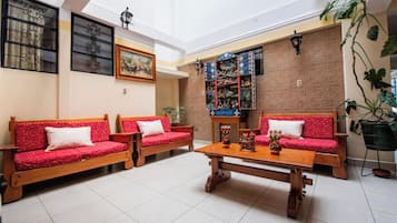 Amplia habitación con dos sofás de madera, una mesa de centro y una pared decorativa con un reloj.