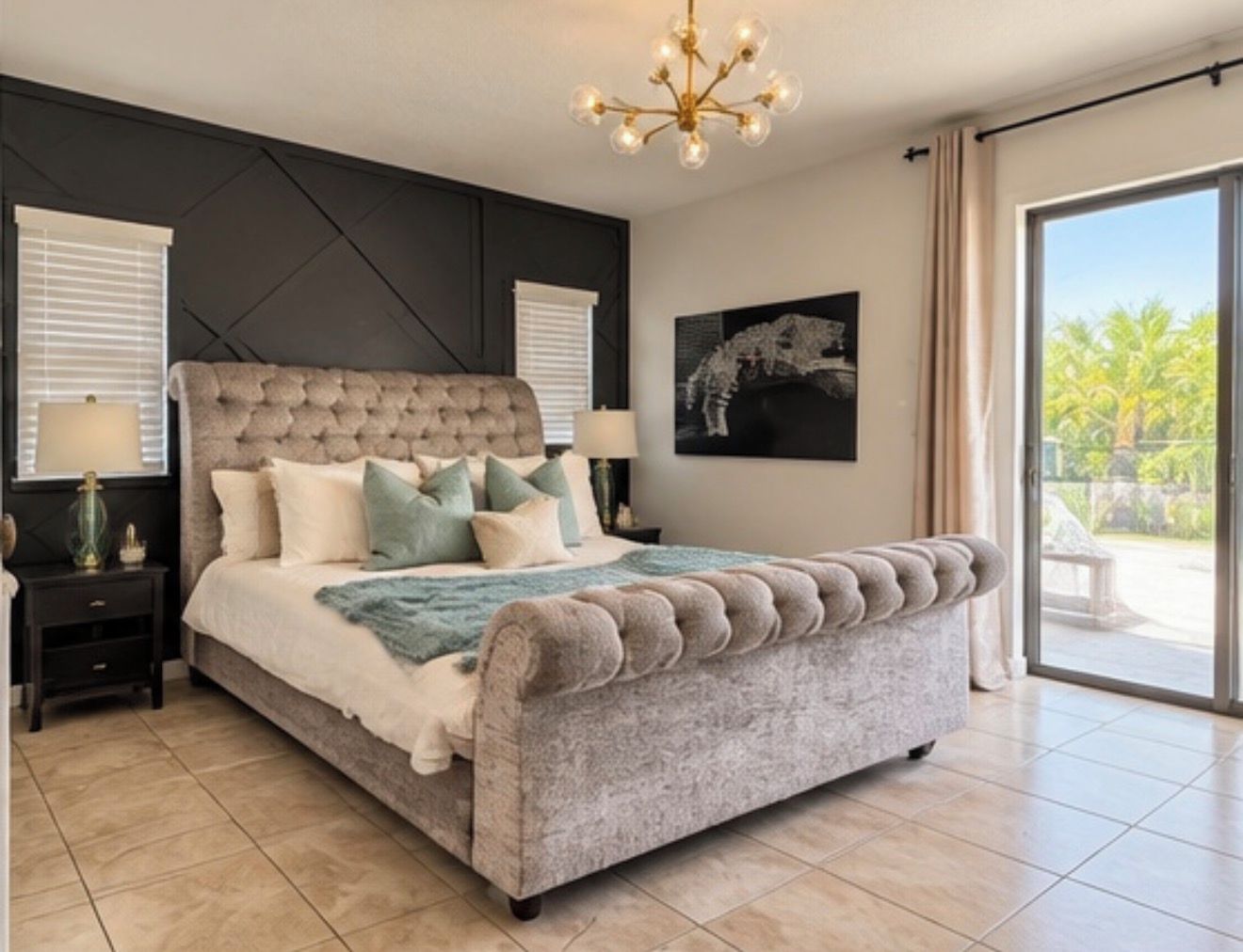 A bedroom with a large bed, a chandelier, and a view of the outdoors.