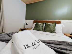 A hotel room with a bed, a headboard, pillows, a blanket, and a nightstand with a lamp. - Boutique Farm Stay | Highland Cow * Horses * Bunnies (Cresco)