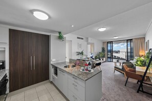 A modern kitchen with a built-in oven, a dining area with a table and chairs, and a large window offering a view of the city. - *Luxe CityScape with River Views* 2b 2ba Sauna Gym (Brisbane City)