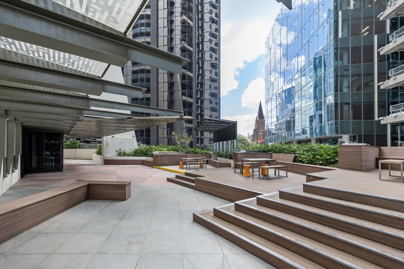 Eine Terrassenanlage im Freien mit Sitzgelegenheiten, Treppen und Blick auf umliegende Gebäude.