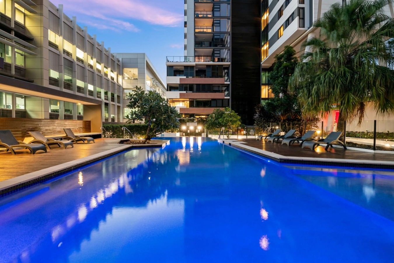 A swimming pool with lounge chairs and a building in the background.