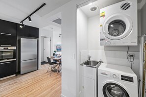 A modern kitchen with a built-in oven, a washing machine, and a sink. - High-End 2BR Haven with Pool, Gym & Parking near South Bank & West End (South Brisbane)