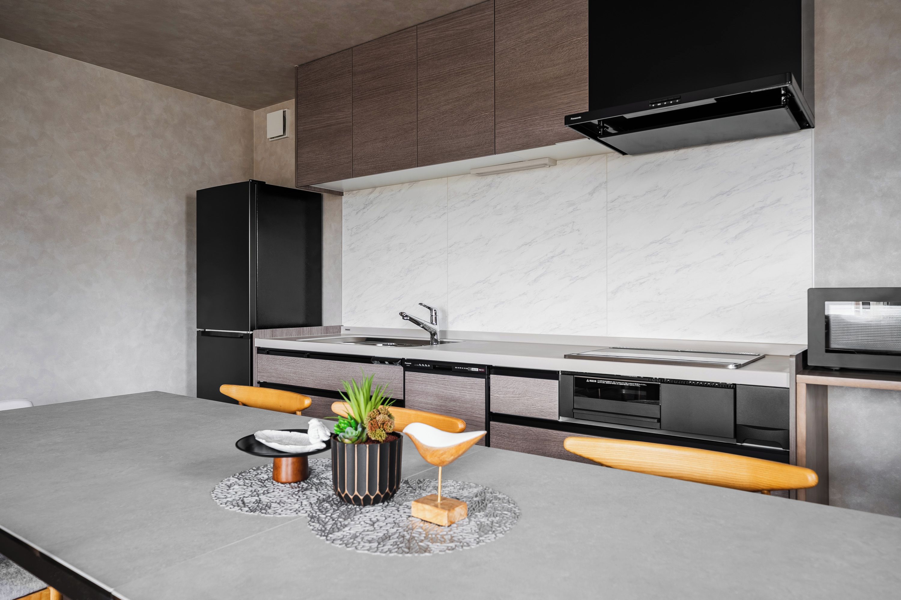 A modern kitchen with a marble backsplash, black cabinets, and a built-in oven.
