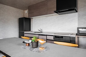 A modern kitchen with a marble backsplash, black cabinets, and a built-in oven.