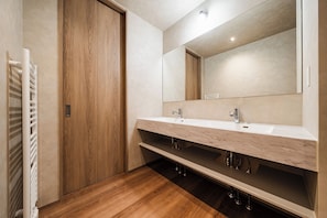 A modern bathroom with a wooden door, a white sink with a marble countertop, and a large mirror. - Furanest (Sorachi-gun)