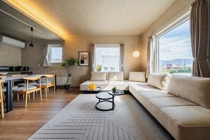 A modern living room with a sofa, coffee table, and dining area.