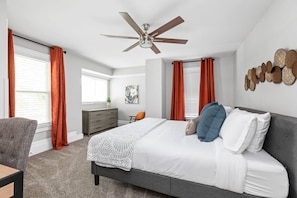 A bedroom with a bed, a desk, a chair, a dresser, and a ceiling fan. - College Ave 6 Bedroom House Sleeps 14 (Indianapolis)