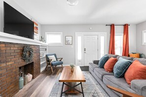 Ett vardagsrum med en öppen spis, en soffa, ett soffbord och en tv.