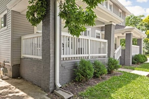 A residential house with a porch, a brick column, and a small garden area. - College Ave 6 Bedroom House Sleeps 14 (Indianapolis)