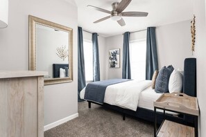 A bedroom with a bed, a desk, a ceiling fan, and a large mirror. - College Ave 6 Bedroom House Sleeps 14 (Indianapolis)