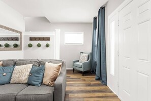 A living room with a grey sofa, a blue armchair, and a wooden floor. - Cozy & Convenient, King Beds, Childrens Museum (Indianapolis)