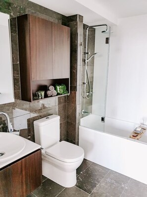 Et moderne badeværelse med toilet, håndvask og brusebad.