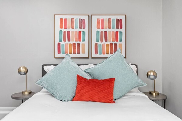 A bed with two pillows, a red one, and two light blue ones, flanked by two bedside lamps on either side. - Earthy Escape - 5 min to downtown (Indianapolis)