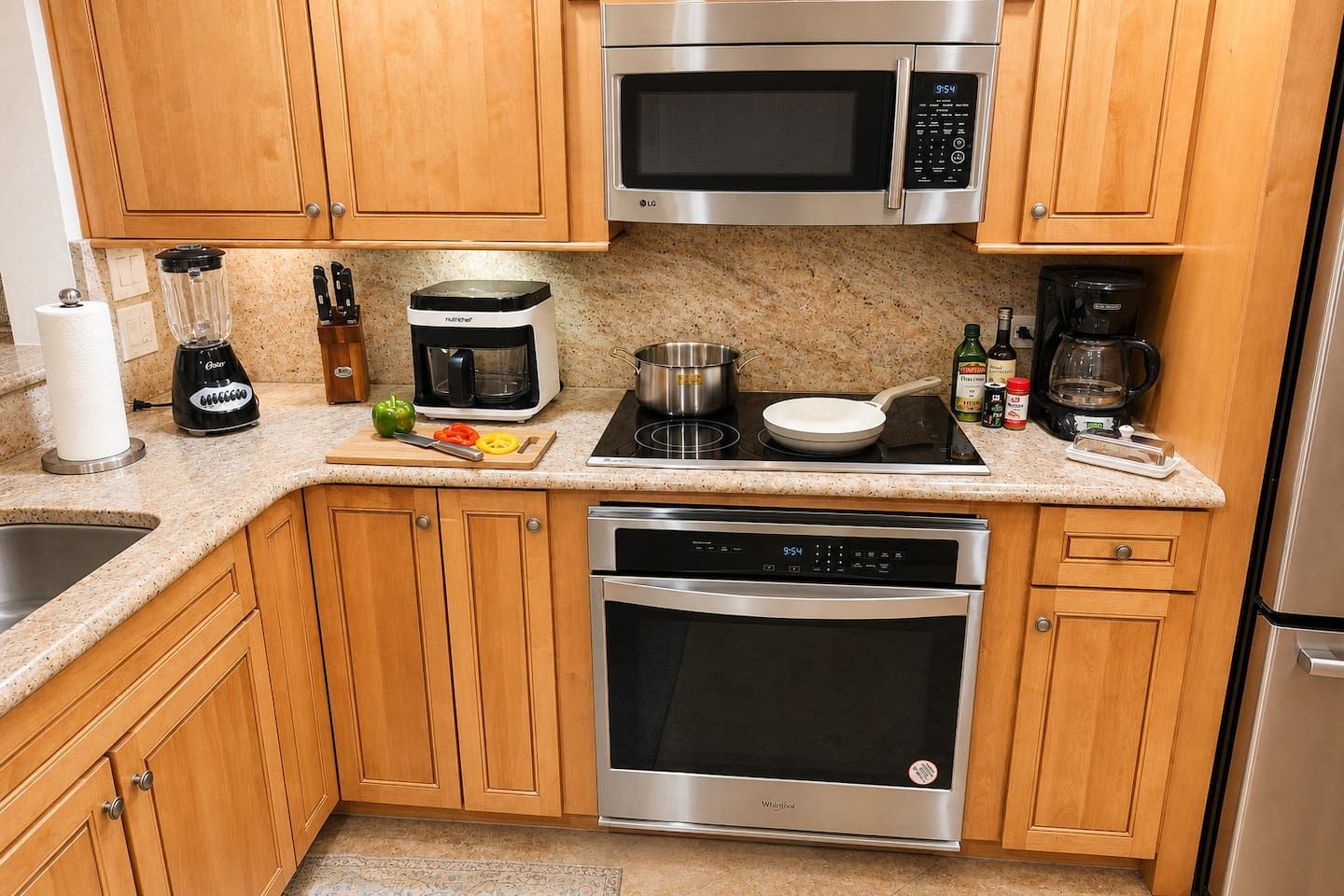 A modern kitchen with stainless steel appliances, wooden cabinets, and a granite countertop.