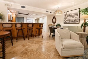 A modern kitchen with a bar area, a dining table with chairs, and a living area with a sofa. - Beachfront View Condo Getaway 2bd2ba Indian Shores (Indian Shores,)