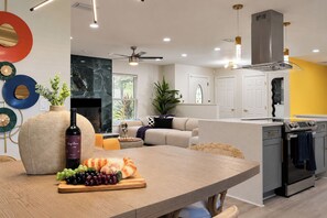 A modern kitchen with a built-in oven, a dining area with a wooden table, and a living room with a sofa and a fireplace. - Clearwater Fun House, Games, Heated Pool, Hot Tub Sleeps12 (Clearwater)