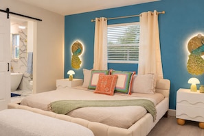 A bedroom with a bed, nightstands, a window with curtains, and wall art. - Clearwater Fun House, Games, Heated Pool, Hot Tub Sleeps12 (Clearwater)
