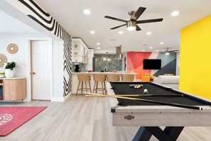 A modern living space with a pool table, kitchen area, and seating. - Clearwater Fun House, Games, Heated Pool, Hot Tub Sleeps12 (Clearwater)