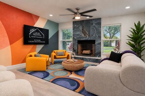 A modern living room with a fireplace, two sofas, a coffee table, and a TV mounted on the wall. - Clearwater Fun House, Games, Heated Pool, Hot Tub Sleeps12 (Clearwater)