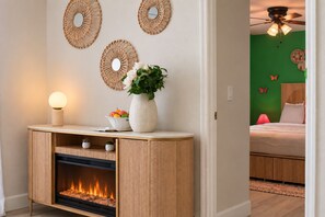 A room with a fireplace, a console table with decorative items, and a green wall with butterfly decorations. - Clearwater Fun House, Games, Heated Pool, Hot Tub Sleeps12 (Clearwater)