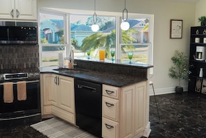 A kitchen with a large window, a built-in oven, and a black dishwasher. - TPA Fun Compound by Airport / Restaurants (Tampa)