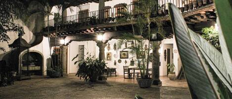 Un patio con un elemento acuático circular, plantas en macetas y un balcón con barandillas.