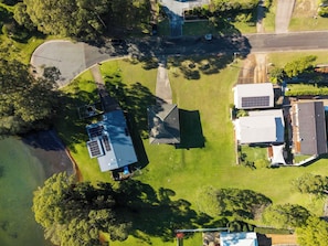 An aerial view of a residential area with houses, a road, and a body of water. - Paradise Lake Conjola Park - Wake up to ocean views (Conjola Park)