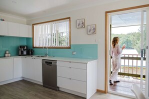 Una cocina moderna con lavavajillas, cafetera y ventana con persianas.