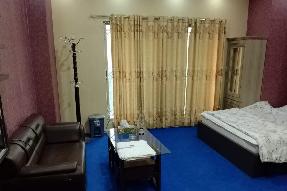 Una camera d'albergo con un letto, un divano, un tavolino e un armadio.