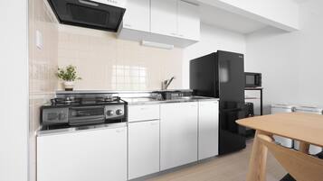 A modern kitchen with white cabinets, a black refrigerator, and a wooden dining table.