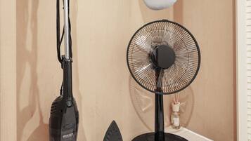 Een stofzuiger, een strijkijzer en een ventilator op een houten plank.