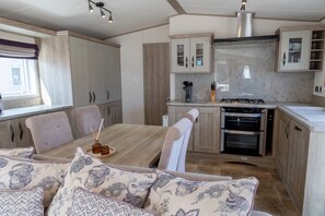 Une cuisine moderne avec un coin repas, comprenant un four encastré, des placards et une fenêtre.