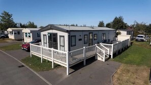 A mobile home with a porch and a carport. - Lodge Sleeps 8 - Hot Tub - Dog Welcome (Lincoln)