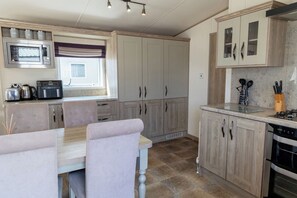 A kitchen with a dining table, chairs, a microwave, cabinets, and a stove. - Lodge Sleeps 8 - Hot Tub - Dog Welcome (Lincoln)