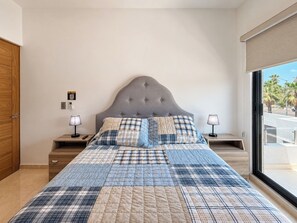 A bedroom with a large bed, two bedside tables, a wooden wardrobe, a window with a view, and a door. - Delfines Duplex Home shared pool (La Paz)