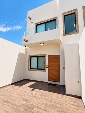A modern two-story building with a flat roof, large windows, and a wooden door. - Delfines Duplex Home shared pool (La Paz)