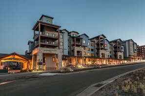 A multi-story hotel with balconies, a stone facade, and a well-lit entrance. - Silverado 106 | Walk to Lifts | Pool | Hot Tub | Fireplace | Sleeps 4 (Park City)