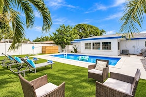 A backyard with a swimming pool, lounge chairs, and a covered patio area. - 🌴Palm Breeze Retreat- Home with a pool, hot tub & game room near Clearwater Beach! (Largo)