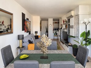 A modern living room with a grey sofa, a dining table with chairs, and a kitchen in the background. - EXCELLENT SITUATION IN FRONT OF THE CITADEL, ON THE OUTSKIRTS OF THE TOWN. 20m FROM THE SEAFRONT AND TO THE BEACH. (Roses)