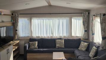A cozy living area with a sectional sofa, a coffee table, and a television on a wooden shelf.