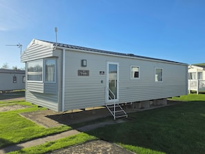 A mobile home with a covered porch, a small attached structure, and a clear sky. - Turnberry holiday park, 18 montrose (Girvan)