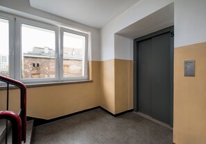 A hallway with a window, a door, and a handrail. - Plac Grzybowski Skyline Studio (Warszawa)