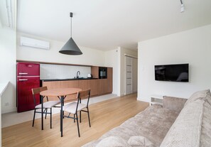 A modern kitchen with a red refrigerator, wooden cabinets, and a black countertop. - Plac Grzybowski Skyline Studio (Warszawa)