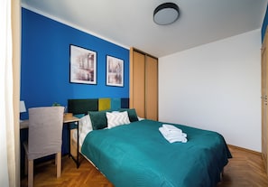 Ein Schlafzimmer mit einem Bett, einem Schreibtisch und zwei gerahmten Bildern an der Wand.