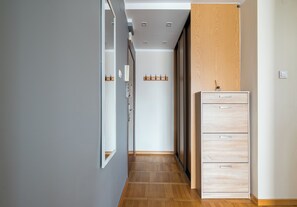 A hallway with a wooden floor, a wardrobe with drawers, a mirror, and a coat rack. - Dolny Mokotów Signature Apartment (Warszawa)