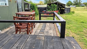 A wooden deck with a table and chairs, surrounded by a metal railing. - Farm Stay, Sleeps 4 w/ Parking near Peterborough (Spalding)