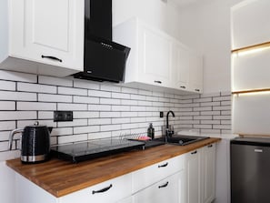 Eine moderne Küche mit weißen Schränken, einer schwarzen Dunstabzugshaube und einer Holz Arbeitsplatte.